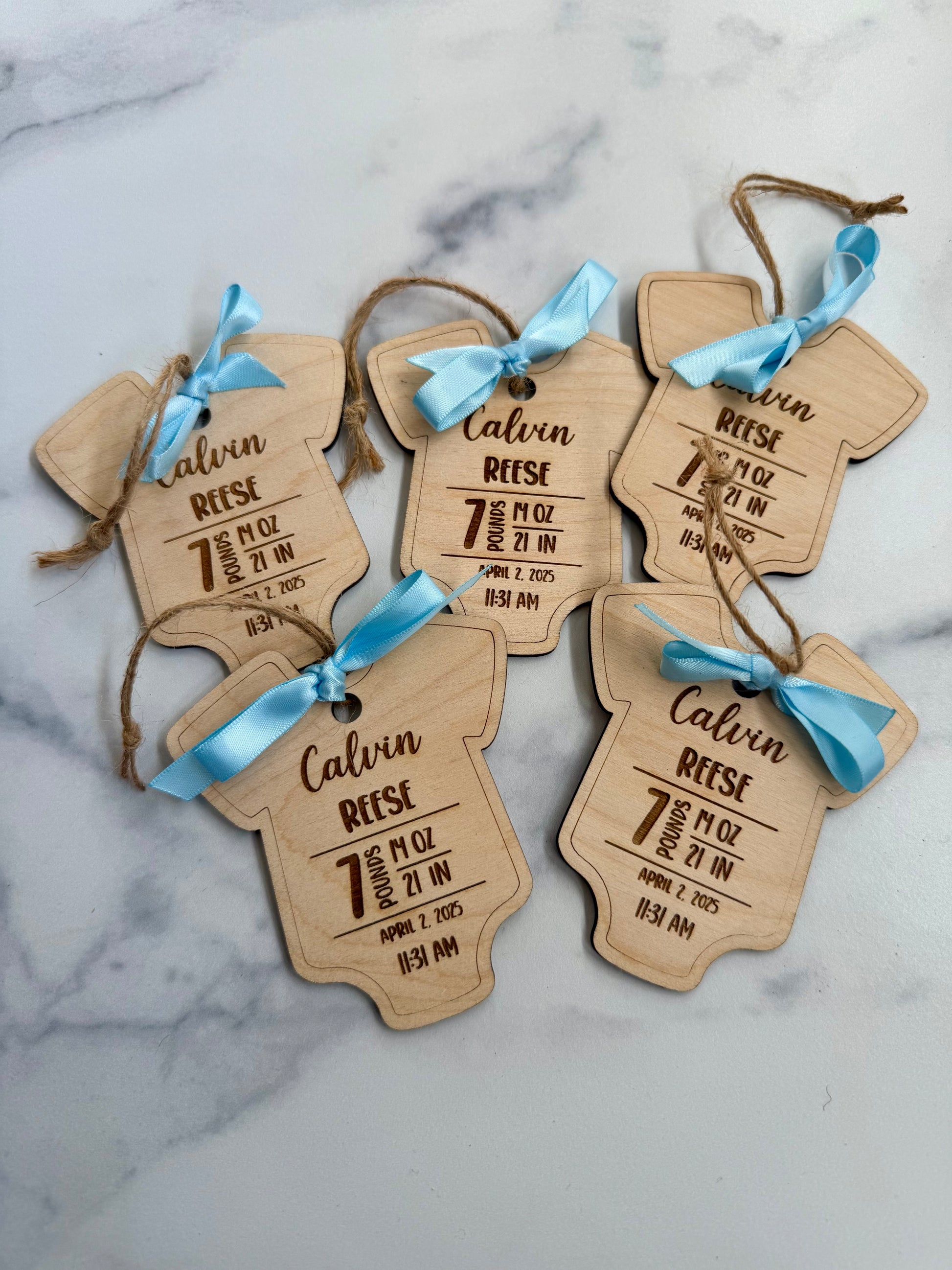 Wooden baby tags with engraved details on a marble surface