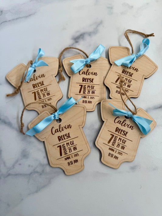 Wooden baby tags with engraved details on a marble surface