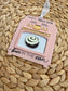 Pink oven-shaped ornament with a bun  and 'bun in the oven' text on a woven surface.