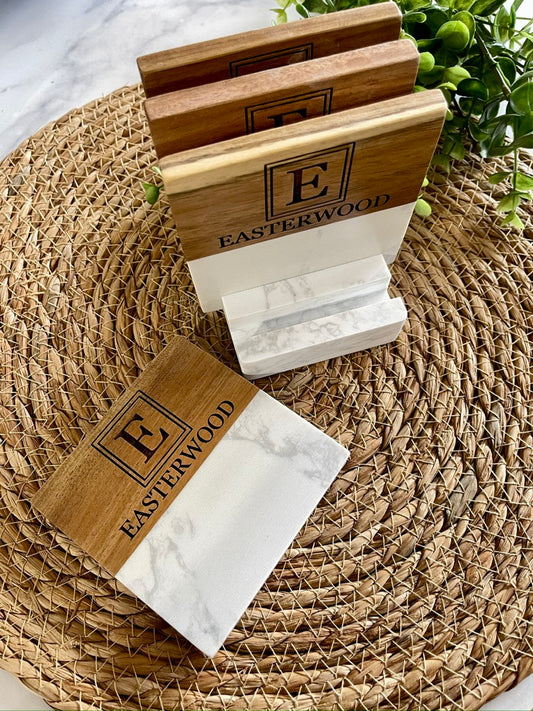 Set of four marble and acacia coasters on a woven mat