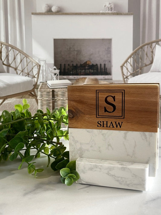 Wooden coaster with 'SHAW' engraving on a marble surface in a living room setting.