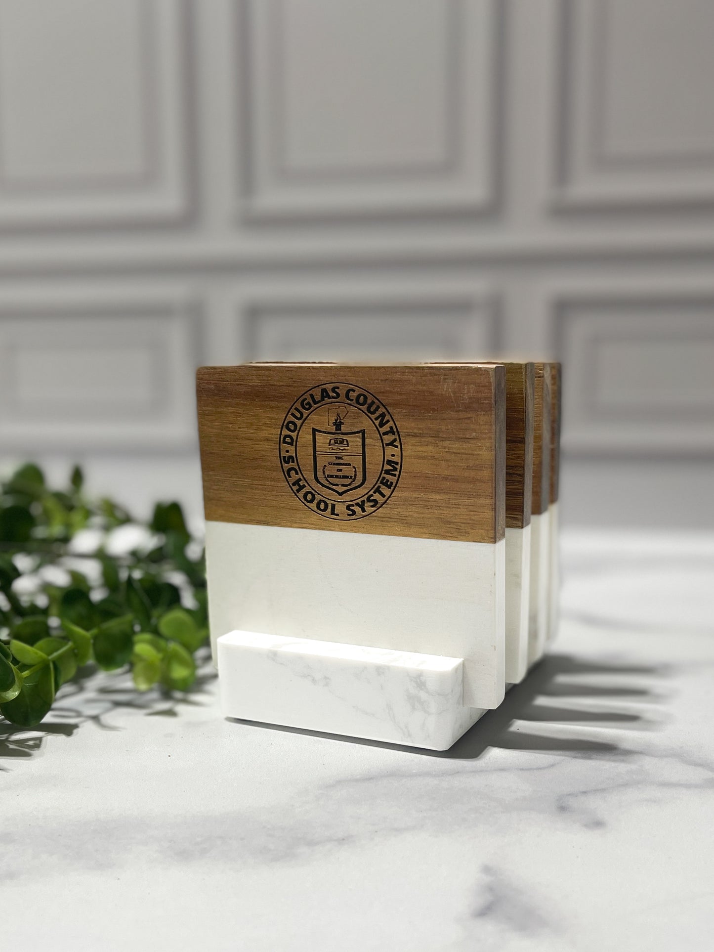 Marble and acacia wood coaster set with engraved logo on a wood surface