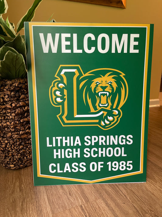 Green sign with Lithia Springs High School Class of 1985 logo on a wooden floor.