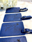Several blue leatherette luggage tags. The tags have blue writing, and they say "Life is a journey. Travel through it with those you love."