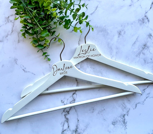 Two white hangers on a marble background with greenery.