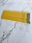 A set of yellow Ticonderoga pencils with orange erasers personalized with a name, placed on a marble surface.